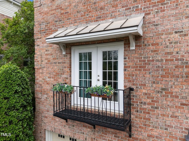 view of exterior entry featuring french doors and brick siding