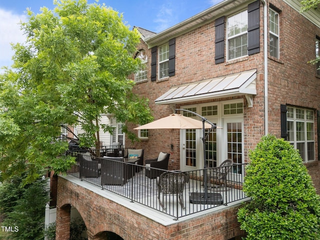 back of house featuring brick siding, french doors, a standing seam roof, and a patio area