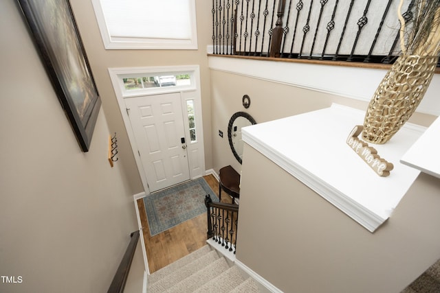 entryway featuring wood finished floors, baseboards, and stairway