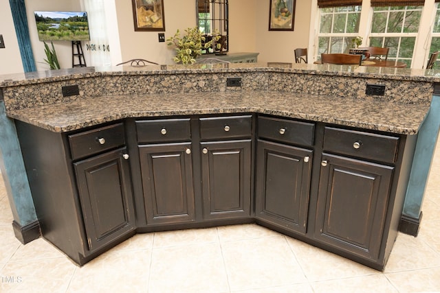 kitchen featuring light tile patterned floors, dark stone countertops, and a kitchen island