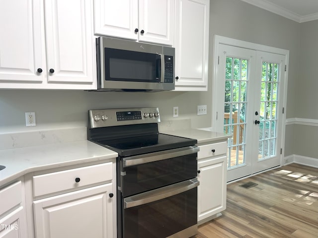 8100 Laurel Mountain Rd, Raleigh, NC 27613 - kitchen with stainless steel appliances, crown molding, white cabinets, light wood finished floors, and light countertops