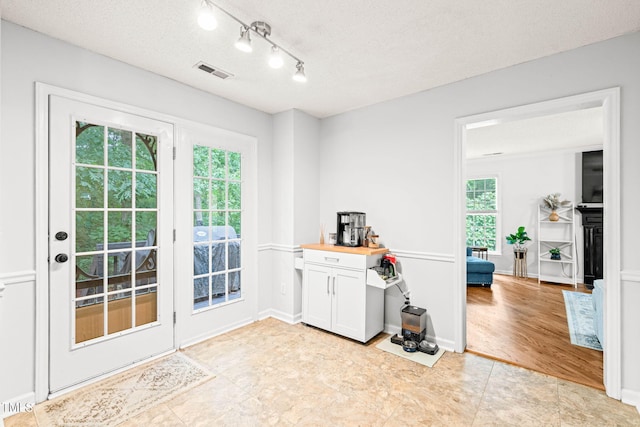 doorway featuring a textured ceiling and rail lighting