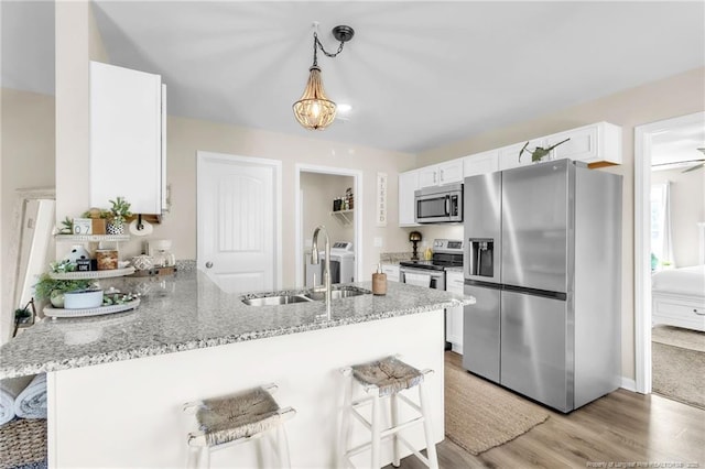 6955 S W St, Godwin, NC 28344 - kitchen with stainless steel appliances, a sink, a peninsula, white cabinets, and light wood finished floors