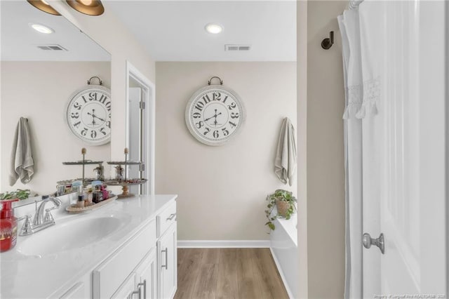 6955 S W St, Godwin, NC 28344 - full bath with vanity, wood finished floors, baseboards, a bath, and recessed lighting