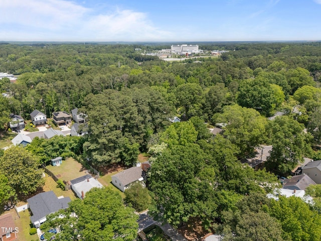 aerial view of property's location featuring a forest and nearby suburban area