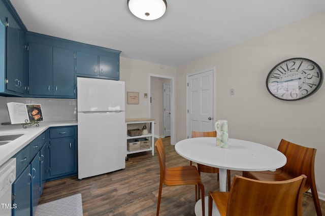 kitchen with freestanding refrigerator, blue cabinets, dark wood-style flooring, and decorative backsplash