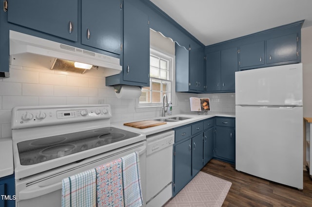 kitchen with white appliances, a sink, under cabinet range hood, blue cabinets, and dark wood-type flooring