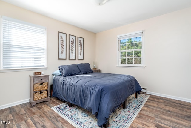 bedroom with wood finished floors, baseboards, and a baseboard radiator