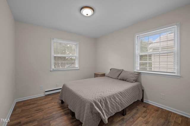 bedroom featuring baseboard heating, multiple windows, wood finished floors, and baseboards