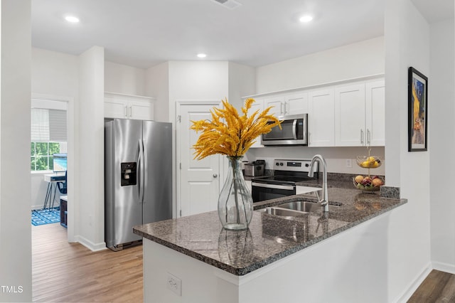4157 Trevino Dr, Durham, NC 27704 - kitchen with stainless steel appliances, a sink, dark stone countertops, light wood finished floors, and baseboards