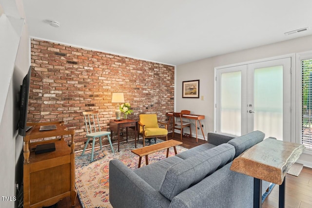 living area with french doors, brick wall, and wood finished floors