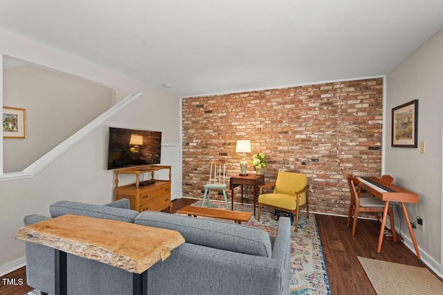 living area with brick wall, dark wood-style floors, and baseboards