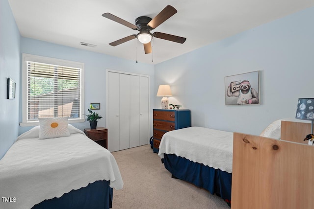 bedroom with light colored carpet, a closet, and a ceiling fan