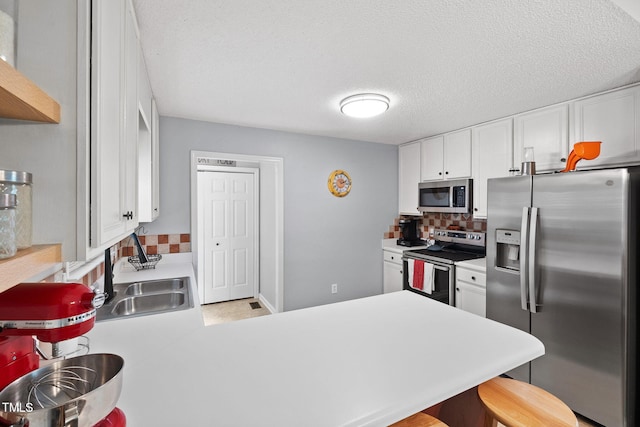 687 W Watson Rd, Benson, NC 27504 - kitchen featuring appliances with stainless steel finishes, a sink, decorative backsplash, a peninsula, and light countertops