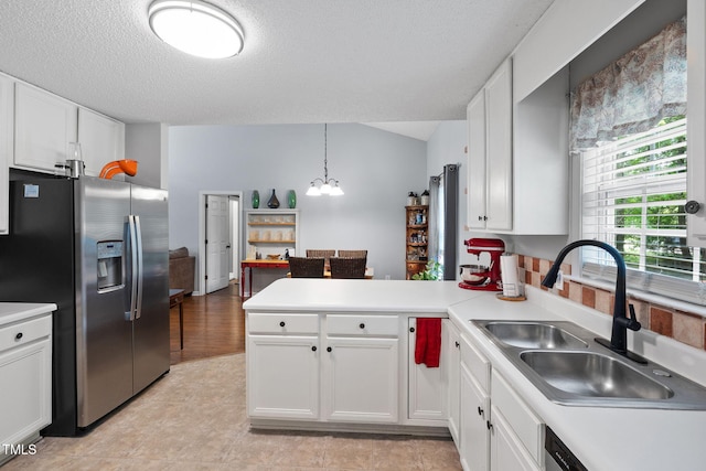 687 W Watson Rd, Benson, NC 27504 - kitchen with stainless steel fridge, a sink, a peninsula, white cabinets, and a chandelier