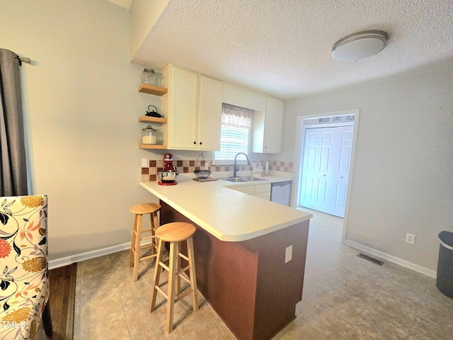 687 W Watson Rd, Benson, NC 27504 - kitchen with stainless steel dishwasher, white cabinetry, open shelves, a kitchen bar, and light countertops