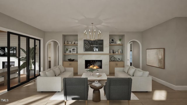 913 Tyrrell Rd, Raleigh, NC 27609 - living room featuring a high end fireplace, wood finished floors, a chandelier, baseboards, and arched walkways
