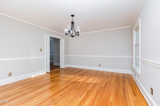 unfurnished room featuring a chandelier, light wood finished floors, baseboards, and crown molding