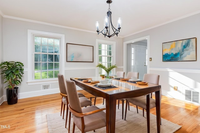 dining space featuring a chandelier, crown molding, light wood-style flooring, and healthy amount of natural light