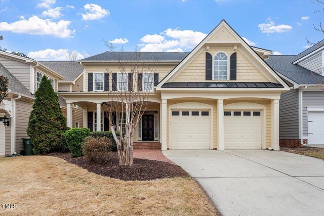 view of front of property with concrete driveway, covered porch, a standing seam roof, and a shingled roof