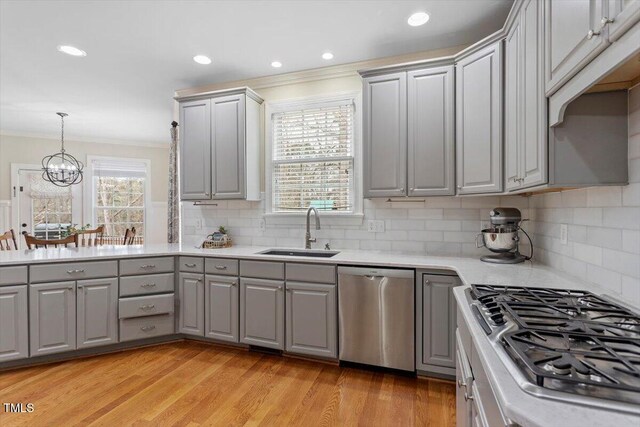 kitchen featuring gray cabinets, appliances with stainless steel finishes, a sink, light countertops, and crown molding