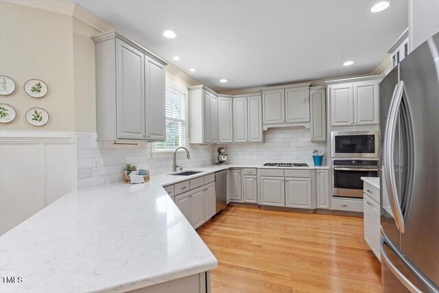 kitchen with appliances with stainless steel finishes, a sink, light countertops, backsplash, and recessed lighting