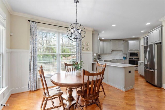 dining area with a chandelier, ornamental molding, light wood-style floors, a decorative wall, and recessed lighting