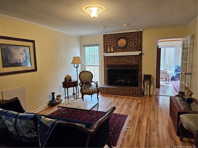 73 Night Heron Ct, Sanford, NC 27332 - living area with crown molding, light wood-style flooring, a textured ceiling, a brick fireplace, and baseboards