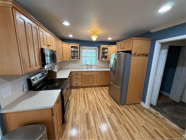 73 Night Heron Ct, Sanford, NC 27332 - kitchen with appliances with stainless steel finishes, a sink, light wood-style flooring, tasteful backsplash, and light countertops