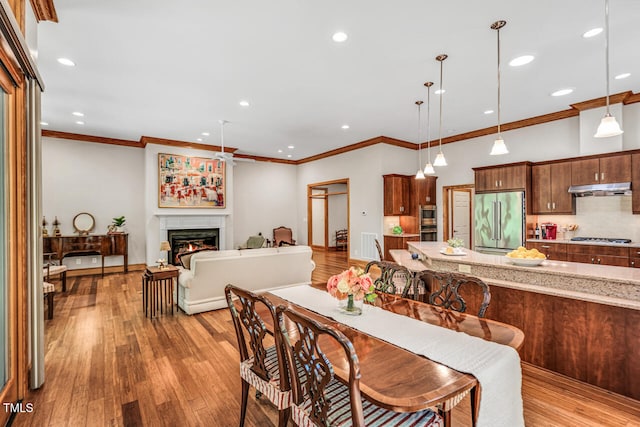 289 Stoneview, Pittsboro, NC 27312 - dining area with a warm lit fireplace, light wood finished floors, recessed lighting, and ornamental molding