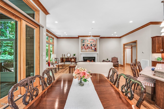 289 Stoneview, Pittsboro, NC 27312 - dining space featuring crown molding, wood finished floors, recessed lighting, a warm lit fireplace, and baseboards