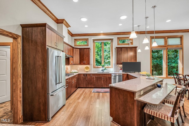 289 Stoneview, Pittsboro, NC 27312 - kitchen featuring stainless steel appliances, a peninsula, ornamental molding, a kitchen bar, and light stone countertops