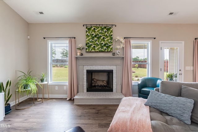 living area with wood finished floors, a brick fireplace, and baseboards