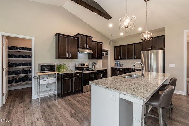 kitchen with stainless steel appliances, a sink, under cabinet range hood, dark wood-style floors, and tasteful backsplash
