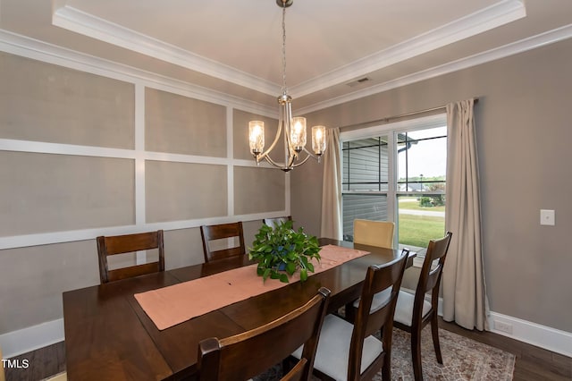 dining space featuring a chandelier, crown molding, a raised ceiling, wood finished floors, and baseboards