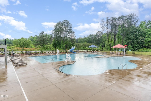 646 Shelford Trl, Zebulon, NC 27597 - community pool with a water slide, a patio, fence, and view of scattered trees
