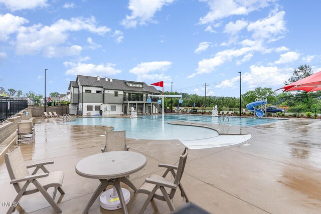 646 Shelford Trl, Zebulon, NC 27597 - community pool featuring a water slide, fence, and a patio area