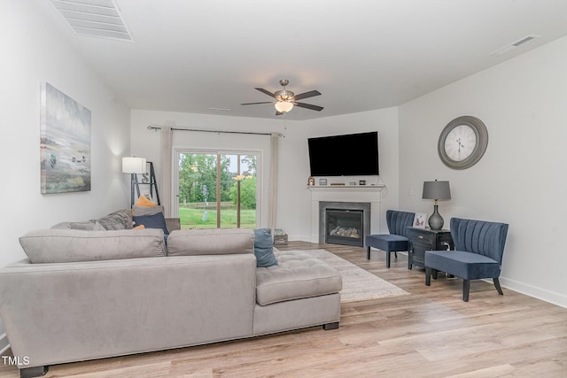 646 Shelford Trl, Zebulon, NC 27597 - living area featuring light wood finished floors, ceiling fan, a glass covered fireplace, and baseboards