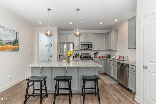 646 Shelford Trl, Zebulon, NC 27597 - kitchen with gray cabinetry, appliances with stainless steel finishes, wood finished floors, tasteful backsplash, and a center island