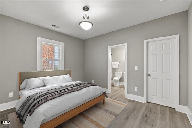 bedroom featuring wood finished floors, baseboards, and connected bathroom