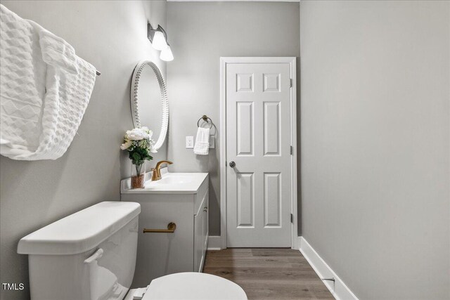 bathroom with wood finished floors, toilet, and vanity