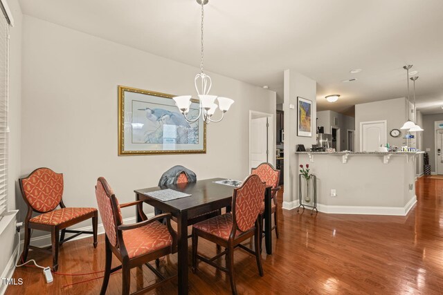 dining area featuring a chandelier, baseboards, and wood finished floors