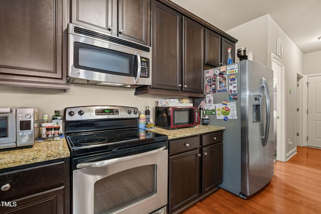 kitchen featuring stainless steel appliances, light wood-type flooring, dark brown cabinetry, and light stone counters