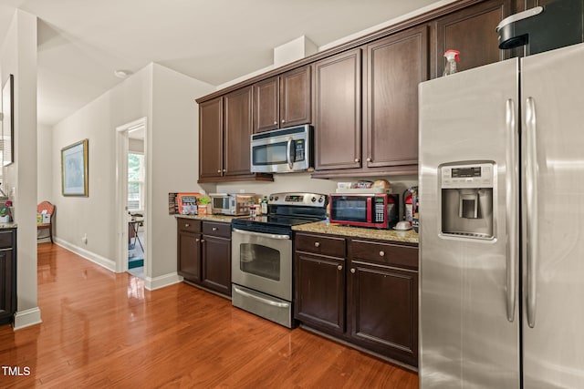 kitchen featuring appliances with stainless steel finishes, light wood-style flooring, and dark brown cabinets