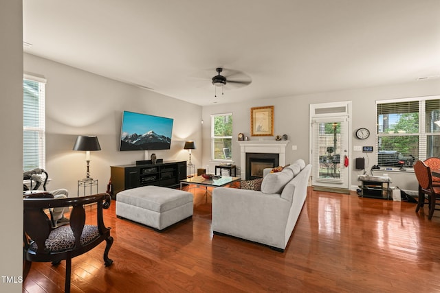 living area featuring ceiling fan, wood finished floors, and a glass covered fireplace
