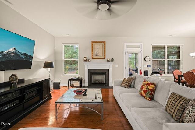 living area with plenty of natural light, wood finished floors, a fireplace with flush hearth, and ceiling fan