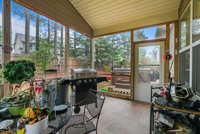 sunroom featuring lofted ceiling, a hot tub, and healthy amount of natural light
