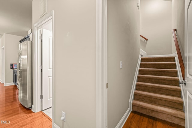 stairs featuring wood finished floors and baseboards