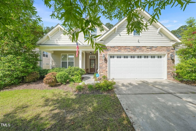 view of front of house featuring an attached garage, driveway, stone siding, and covered porch