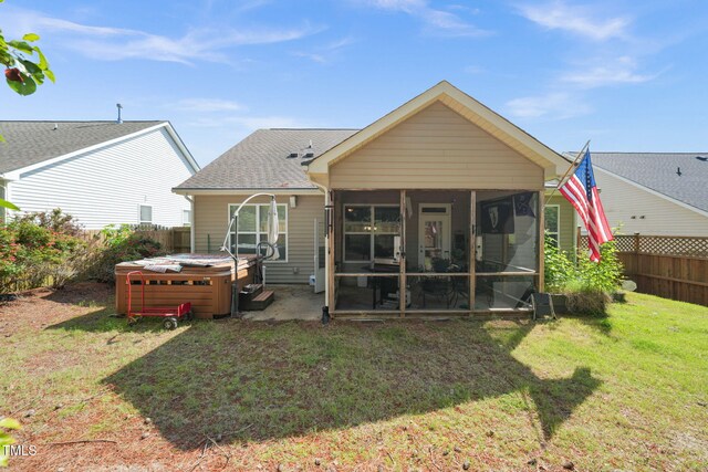 rear view of property featuring a hot tub, a sunroom, and a shingled roof